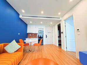 A modern living room with a sofa and a dining table, a kitchen in the background, and a door leading to another room. - VietStay Vietnam (Phu Quoc)