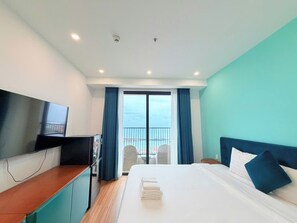 A hotel room with a bed, a TV, a desk, and a balcony with a view. - VietStay Vietnam (Phu Quoc)