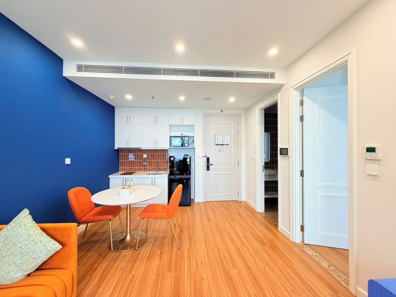 A modern interior with a dining area, kitchen, and a blue accent wall.