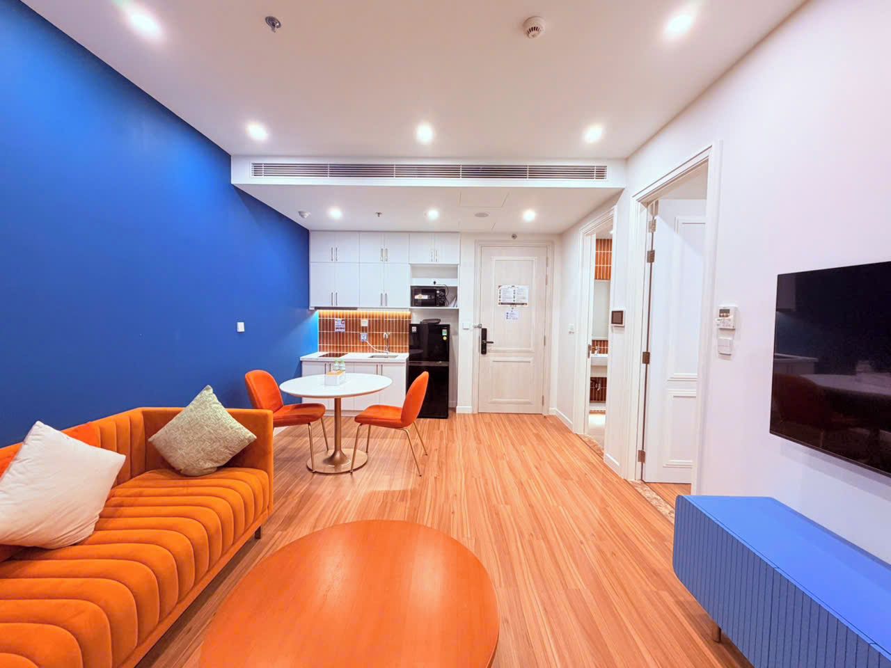 Una sala moderna con un sofá, una mesa de comedor y una cocina al fondo.