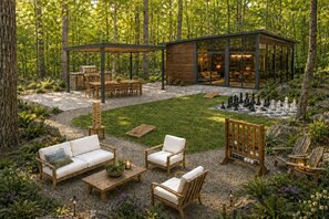 A modern outdoor patio with a wooden deck, seating area, and a glass-enclosed structure. - Private 1BR Mountain Cabin with Hot Tub & Forest Views (Menlo)