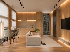 A modern interior with a sofa, dining table, and chairs, wooden flooring, and a large TV on the wall. - Private 1BR Mountain Cabin with Hot Tub & Views (Menlo)
