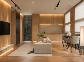 A modern living room with a sofa, a coffee table, and a dining area with chairs. - Private 1BR Mountain Cabin with Hot Tub & Views (Menlo)