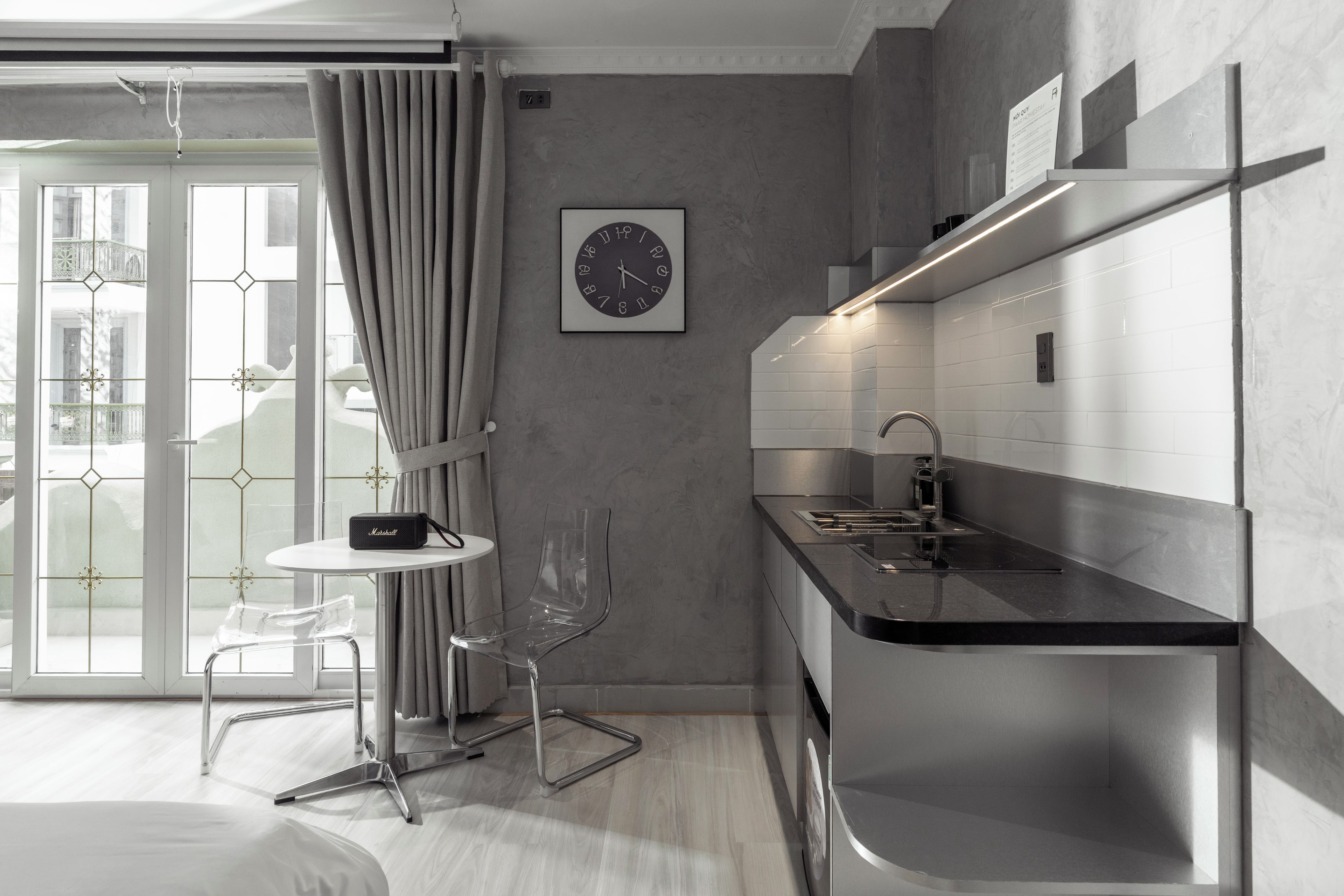 A modern kitchen with a black countertop, stainless steel appliances, and a clear glass chair.