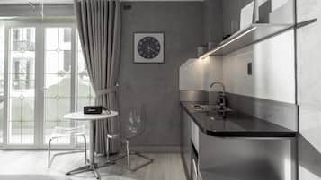 A modern kitchen with a black countertop, stainless steel appliances, and a clear glass chair.