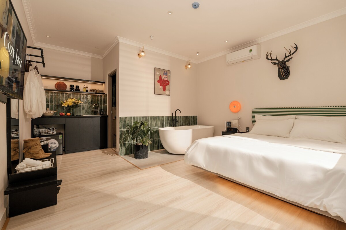 Une chambre moderne dotée d’un grand lit, d’une baignoire et d’un petit coin cuisine avec un évier et un plan de travail.