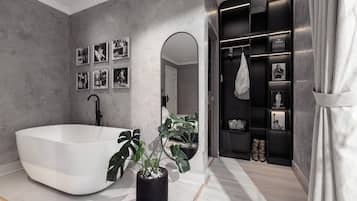 A modern bathroom with a freestanding bathtub, a large mirror, and a vanity with a black shelf displaying various items.