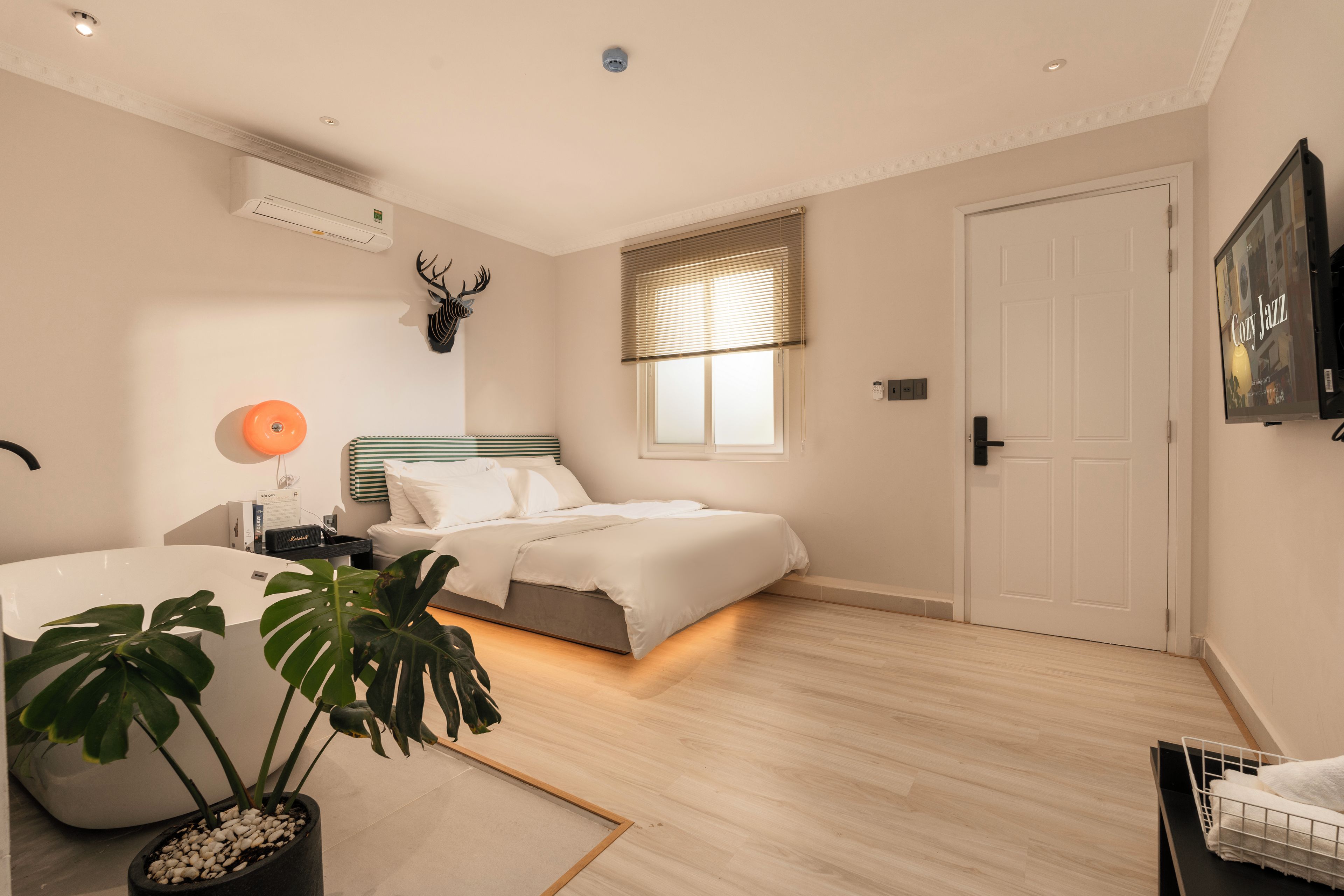 Un dormitorio moderno con cama, mesita de noche, lámpara y una decoración de cabeza de ciervo montada.