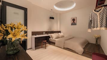 A modern bedroom with a bed, bedside table, and a desk area.