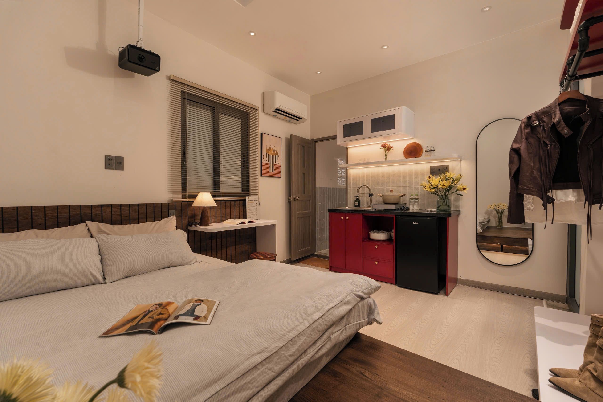 Un dormitorio moderno con una cama grande, mesita de noche, lámpara y una revista.