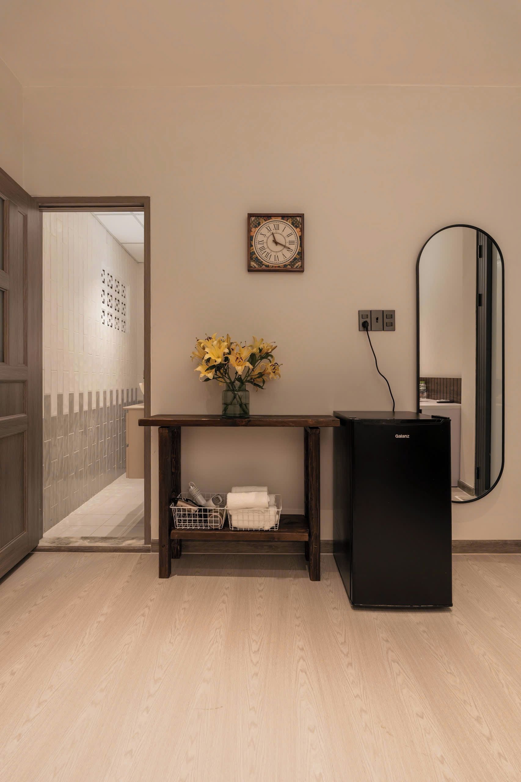 A bathroom with a wooden vanity, a black sink, a mirror, and a clock on the wall.