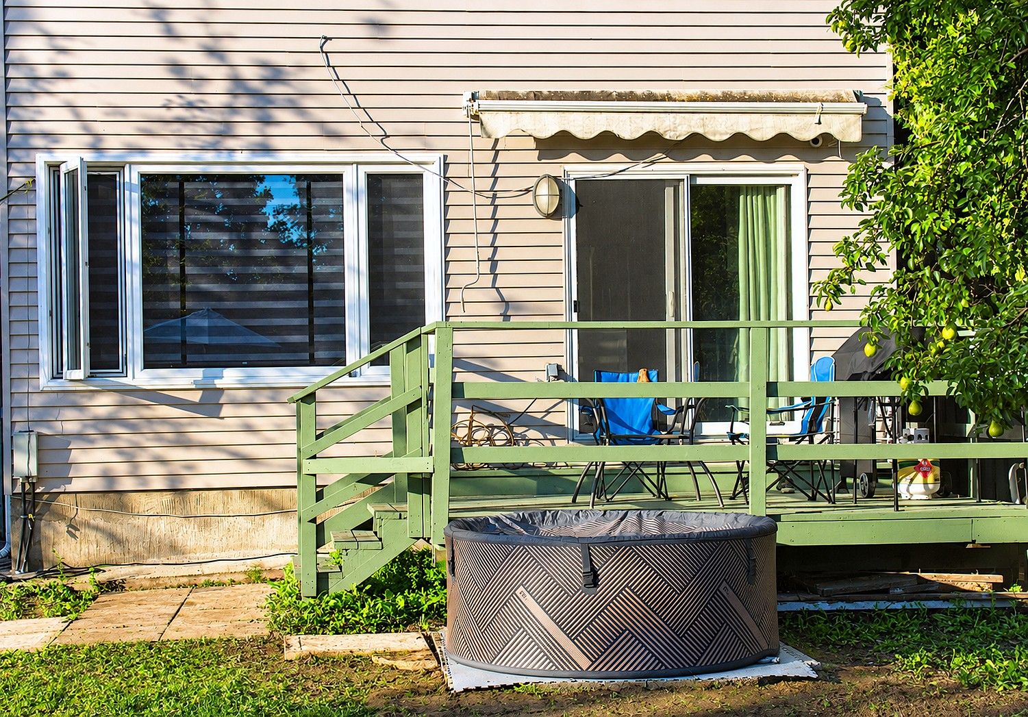 Une maison avec un porche verdoyant, un espace de détente extérieur abrité et un grand ventilateur extérieur.