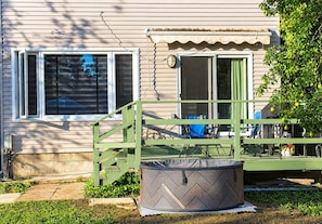 A house with a green porch, a covered outdoor seating area, and a large outdoor fan.