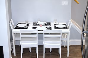 A dining area with a white table set for four, including plates, glasses, and cutlery.
