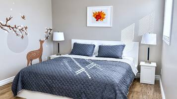 A bedroom with a bed, two bedside tables, a wall-mounted lamp, and a framed picture.