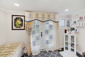 Ein Zimmer mit einem Bett, einer Glastür, einem Ablagefach für Toilettenartikel und einem gerahmten Bild an der Wand.