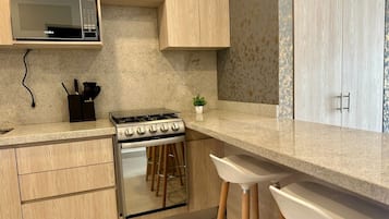 A modern kitchen with a built-in stove, microwave, and wooden cabinets.