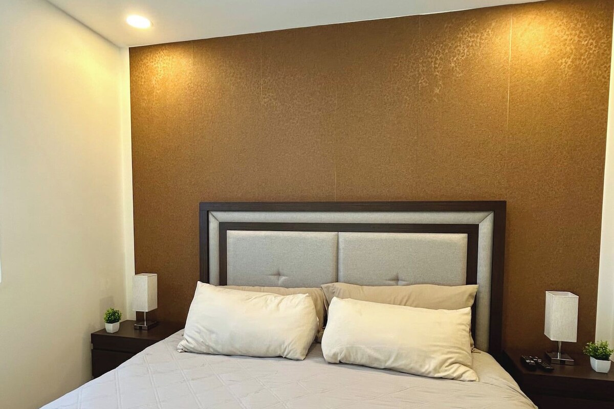 Quarto de hotel com uma cama grande, duas mesas de cabeceira e uma cabeceira.