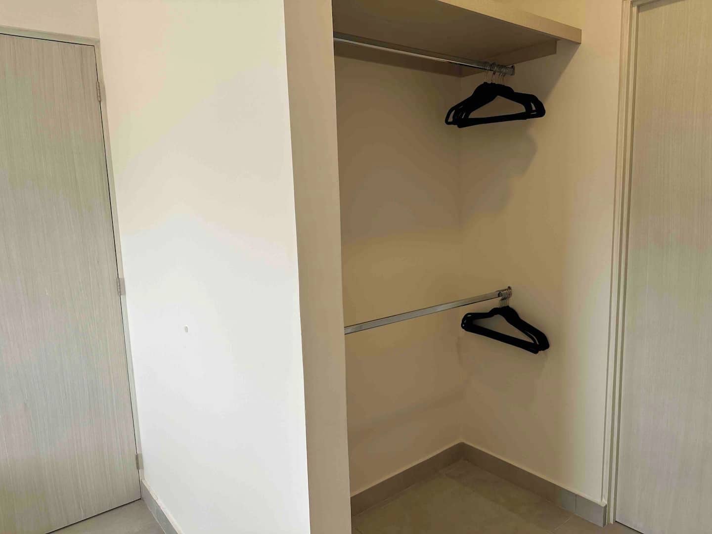 A closet with two hangers on a rod and a door to the left.