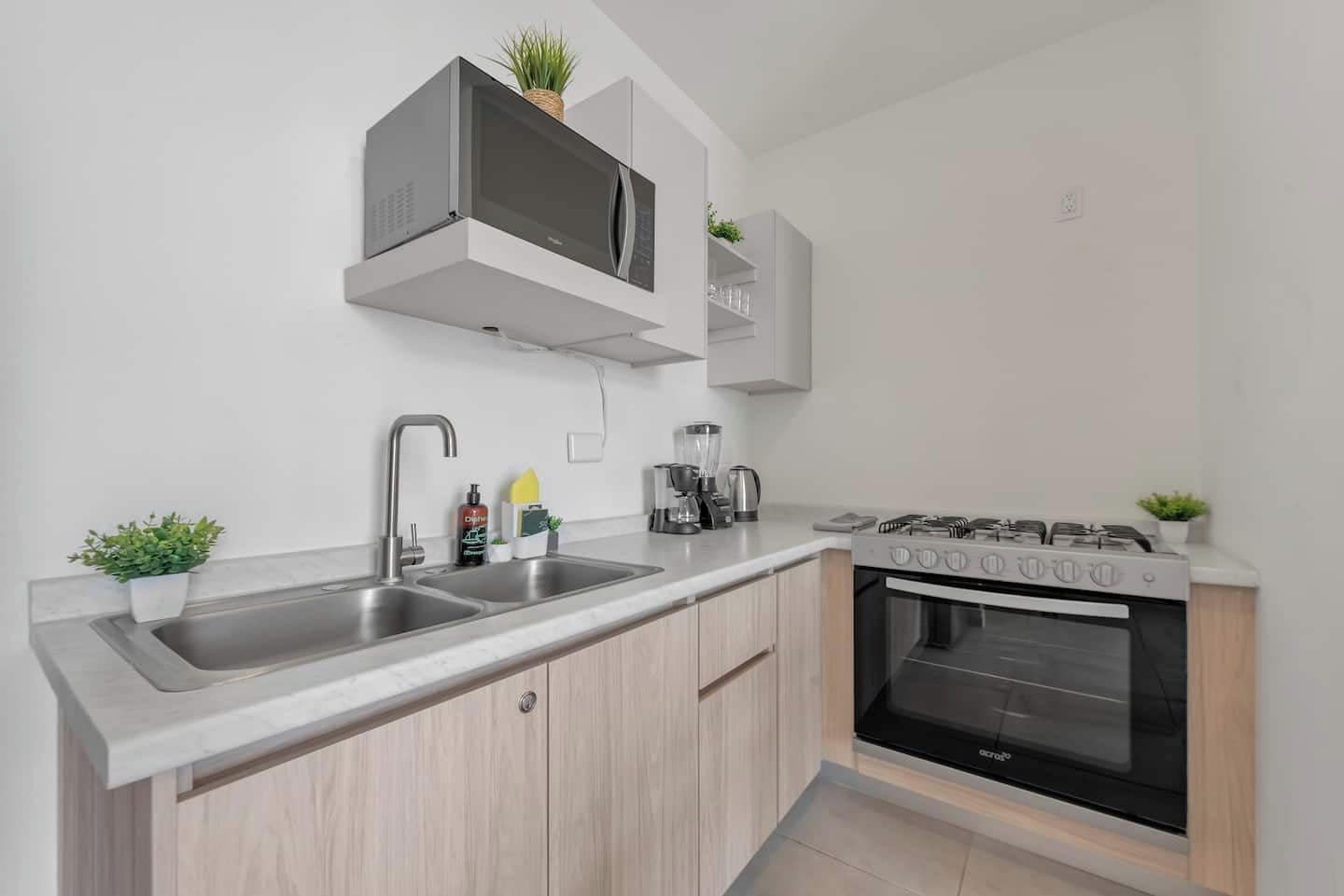 Una cocina moderna con microondas integrado, pileta doble y estufa a gas.
