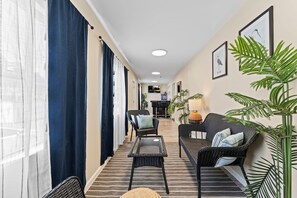 Ein Flur mit einer Couch, Sesseln und einem Tisch, der zu einer Bar führt.