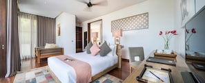 A modern hotel room with a large bed, a desk with a laptop, a chair, a bedside table with a lamp, and a view of a cityscape. - Casa Brio - Private Chef Villa for 8 till 10, Floating Breakfast, Seminyak (Bali)