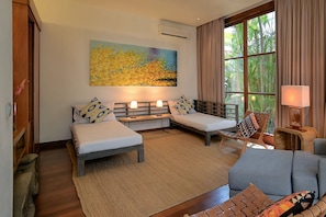 A hotel room with two beds, a sofa, a window with curtains, and a painting on the wall. - Casa Brio - Private Chef Villa for 8 till 10, Floating Breakfast, Seminyak (Bali)