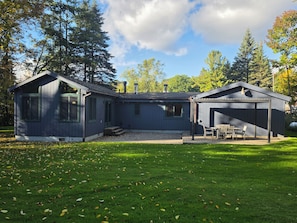 Ein zweistöckiges Haus mit überdachter Veranda und kleiner Terrasse.