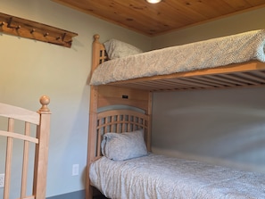 A bunk bed with a patterned bedspread, a wooden headboard, and a wooden ceiling with a light fixture. - Caberfae Cabin - 3BR Next to Caberfae Peaks Ski & Golf Resort (Cadillac)