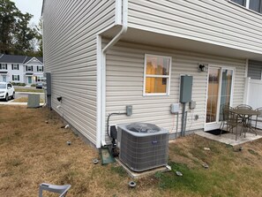 A residential exterior with siding, a window, an air conditioning unit, and a patio area.
