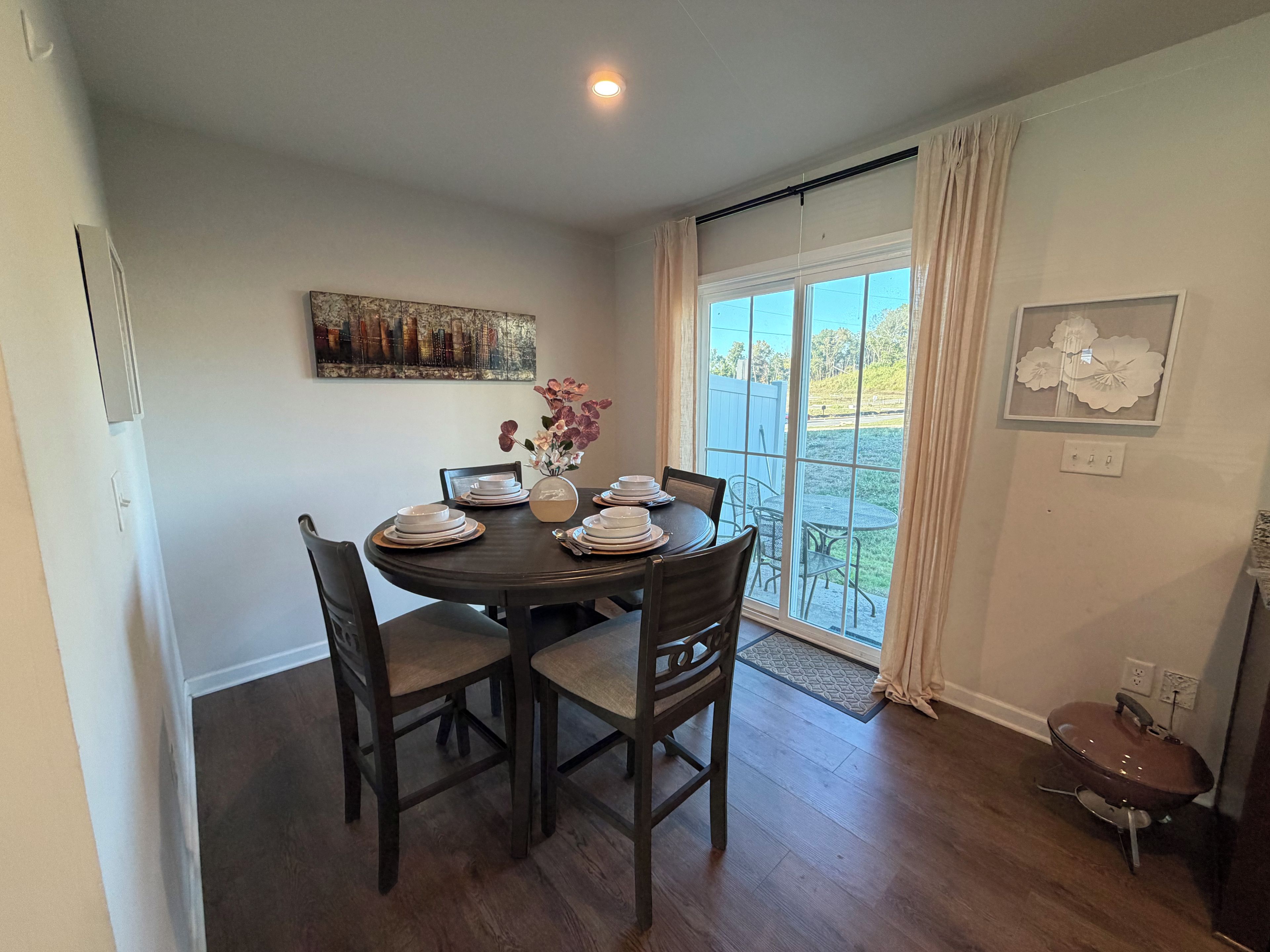 A dining area with a round table, chairs, and a window with curtains.
