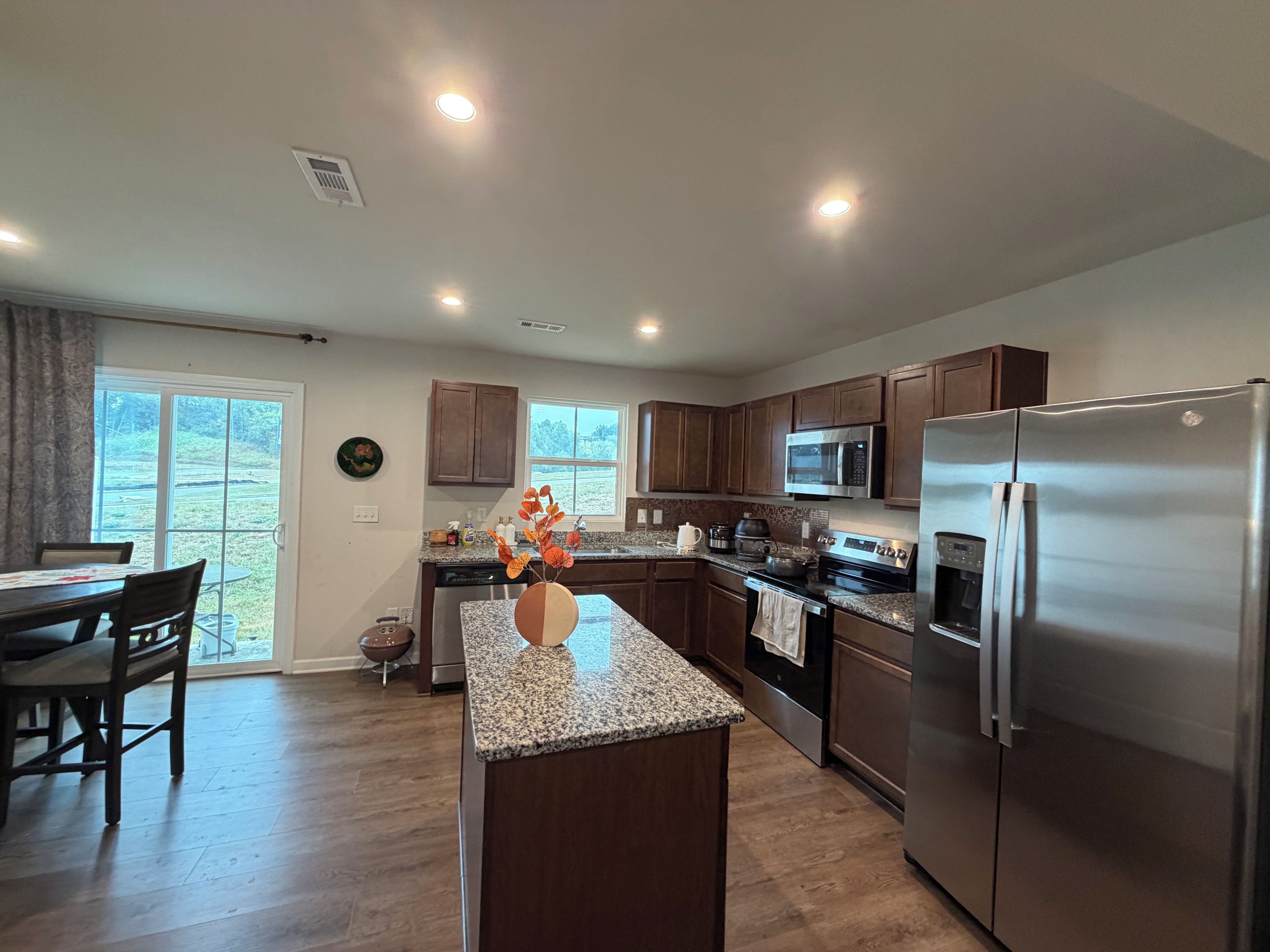 A modern kitchen with granite countertops, stainless steel appliances, and wooden cabinets.