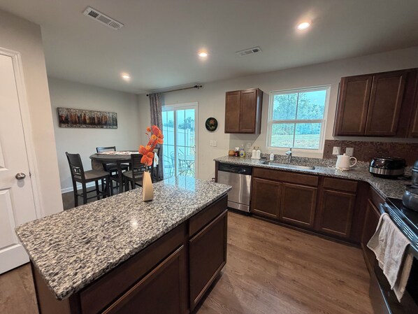 A kitchen with granite countertops, wooden cabinets, a dishwasher, a sink, and a window.