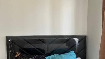 Een bed met een zwart hoofdeinde, beddengoed met een bloemenprint en twee kussens.