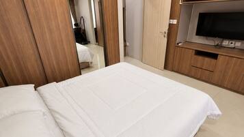 Habitación de hotel con una cama grande, armario de madera y televisor.
