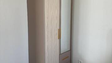 Een kamer met een kledingkast, een bed met een bloemenprint en een witte muur.