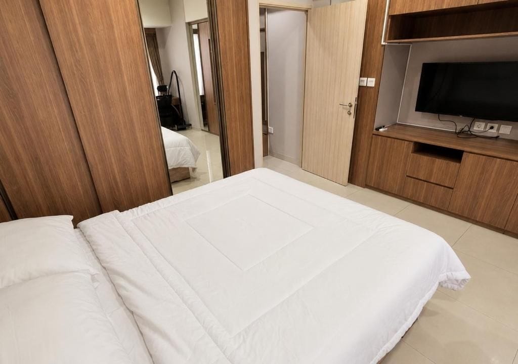 A hotel room with a bed, a television, and wooden furniture.