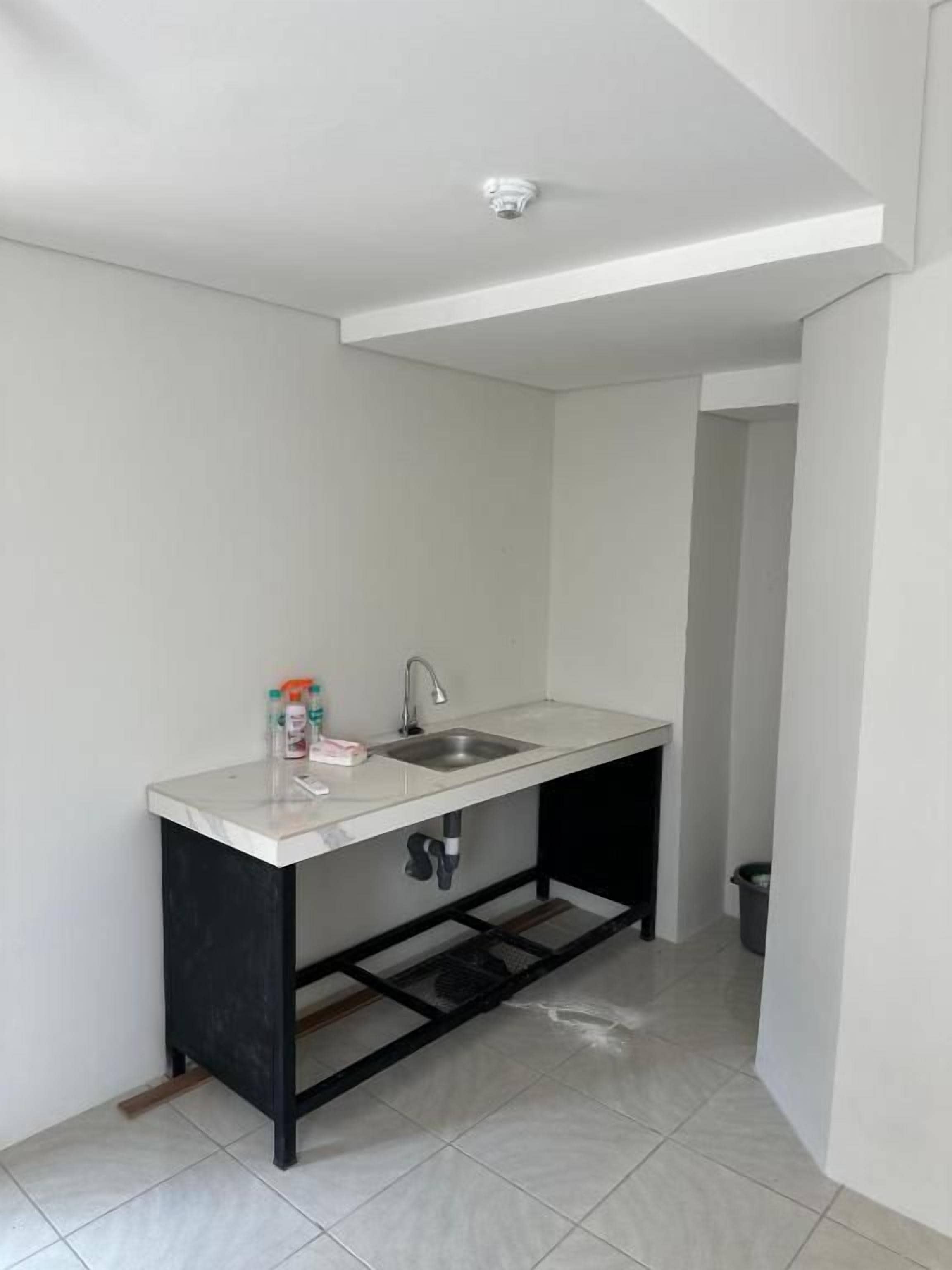 A small kitchen with a white countertop, a sink, and a black metal frame.