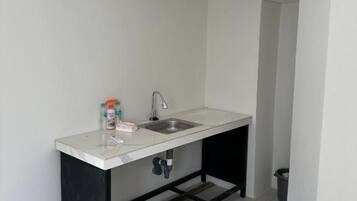 A small kitchen with a white countertop, a sink, and a black metal frame.