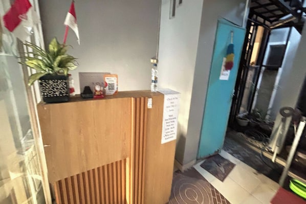 A reception desk with a potted plant, a framed certificate, and a sign with contact information.