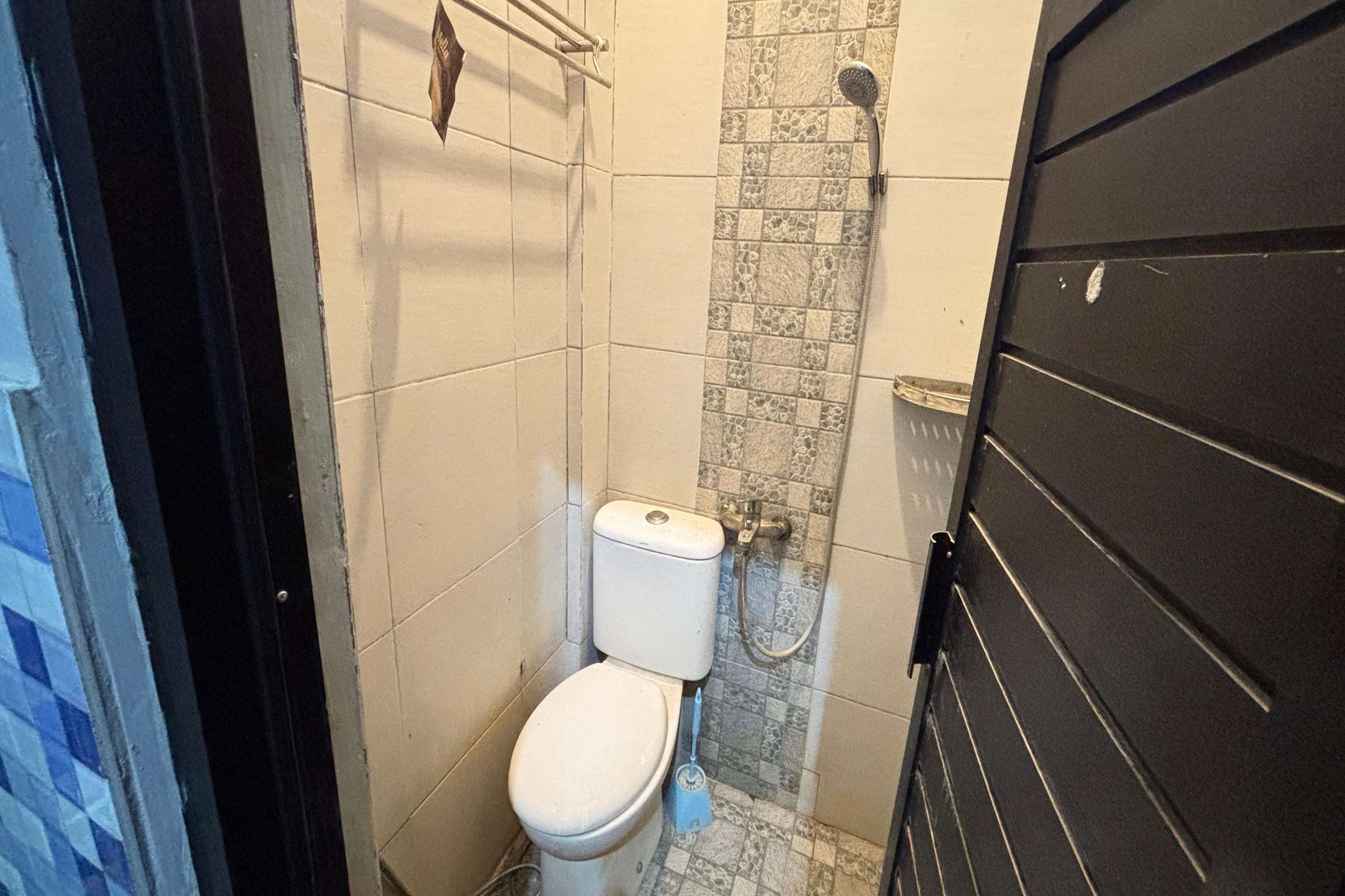 A small bathroom with a toilet, a shower, and a tiled wall.
