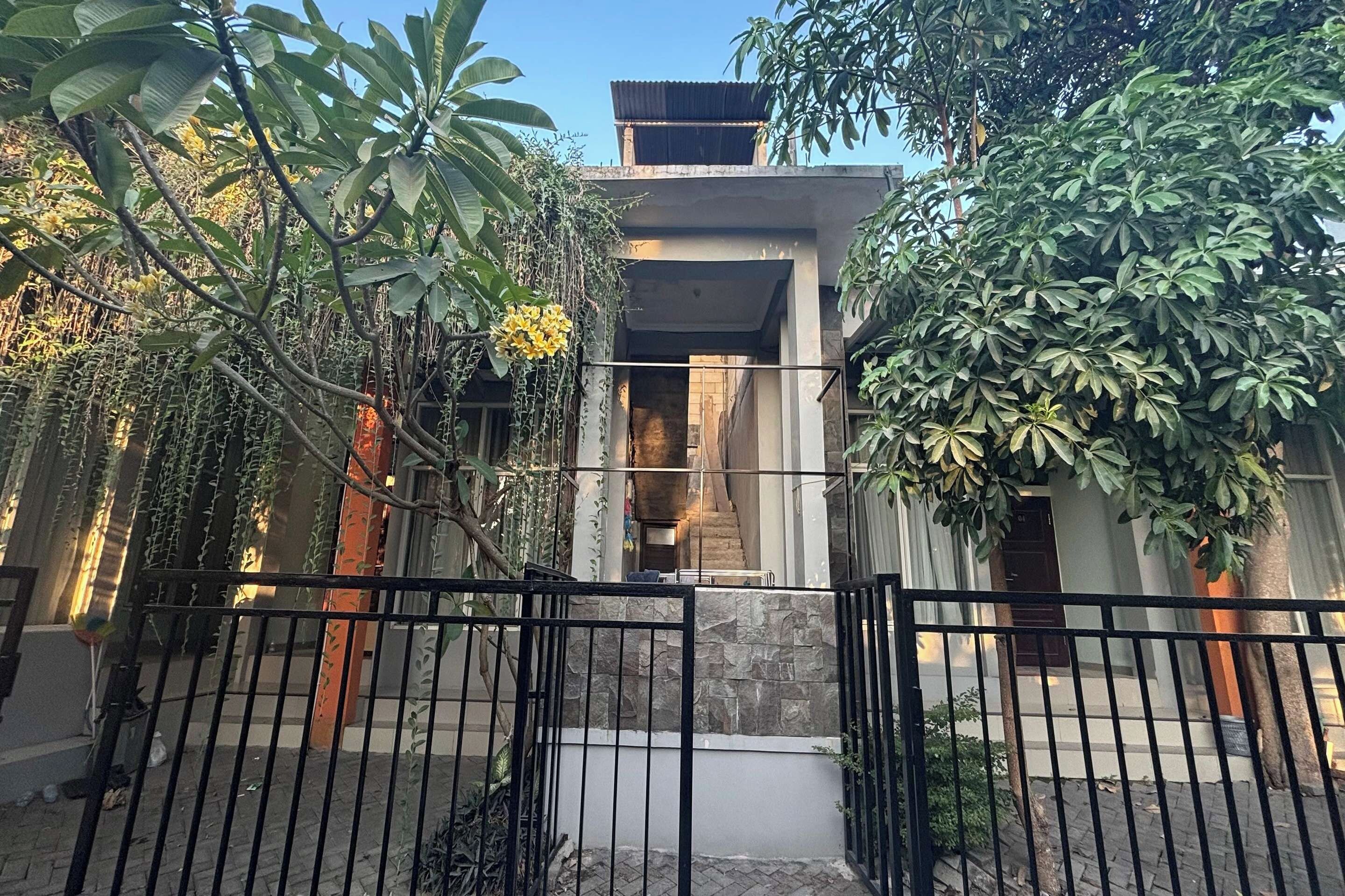 Uma entrada fechada por portão para um edifício com fachada de pedra e uma escadaria que leva a um andar superior.