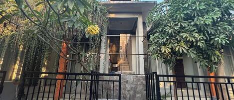 A gated entrance to a building with a stone facade and a staircase leading to an upper level.