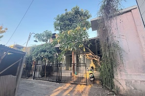 A residential area with a gated entrance, a tree with yellow flowers, and a parked scooter.