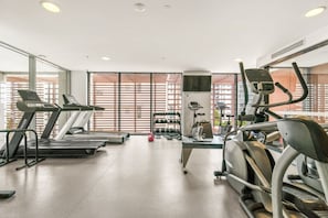 A gym with treadmills, elliptical machines, and free weights. - Refined One Bedroom Retreat (Fortitude Valley)