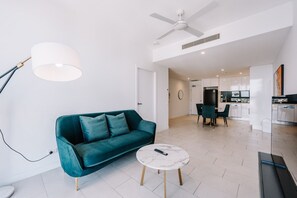 A modern living room with a teal sofa, a round coffee table, and a ceiling fan. - Refined One Bedroom Retreat (Fortitude Valley)