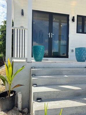 A white building with a set of concrete steps leading to a door with a sign that reads 'Sail Away.' - Cozy studio in walking distance to restaurants, marinas, coffee shop & groceries (Marsh Harbour)