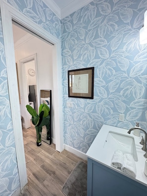A bathroom with a sink, a mirror, a framed picture on the wall, and a potted plant. - Cozy studio in walking distance to restaurants, marinas, coffee shop & groceries (Marsh Harbour)
