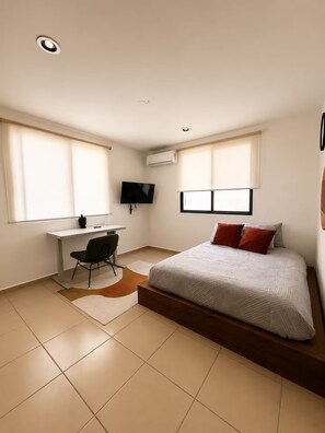 A bedroom with a bed, a desk, a chair, a TV, and an air conditioning unit. - Cumbres Novonorte: Private Pool, Covered Terrace & 3 Bedrooms (Mérida)