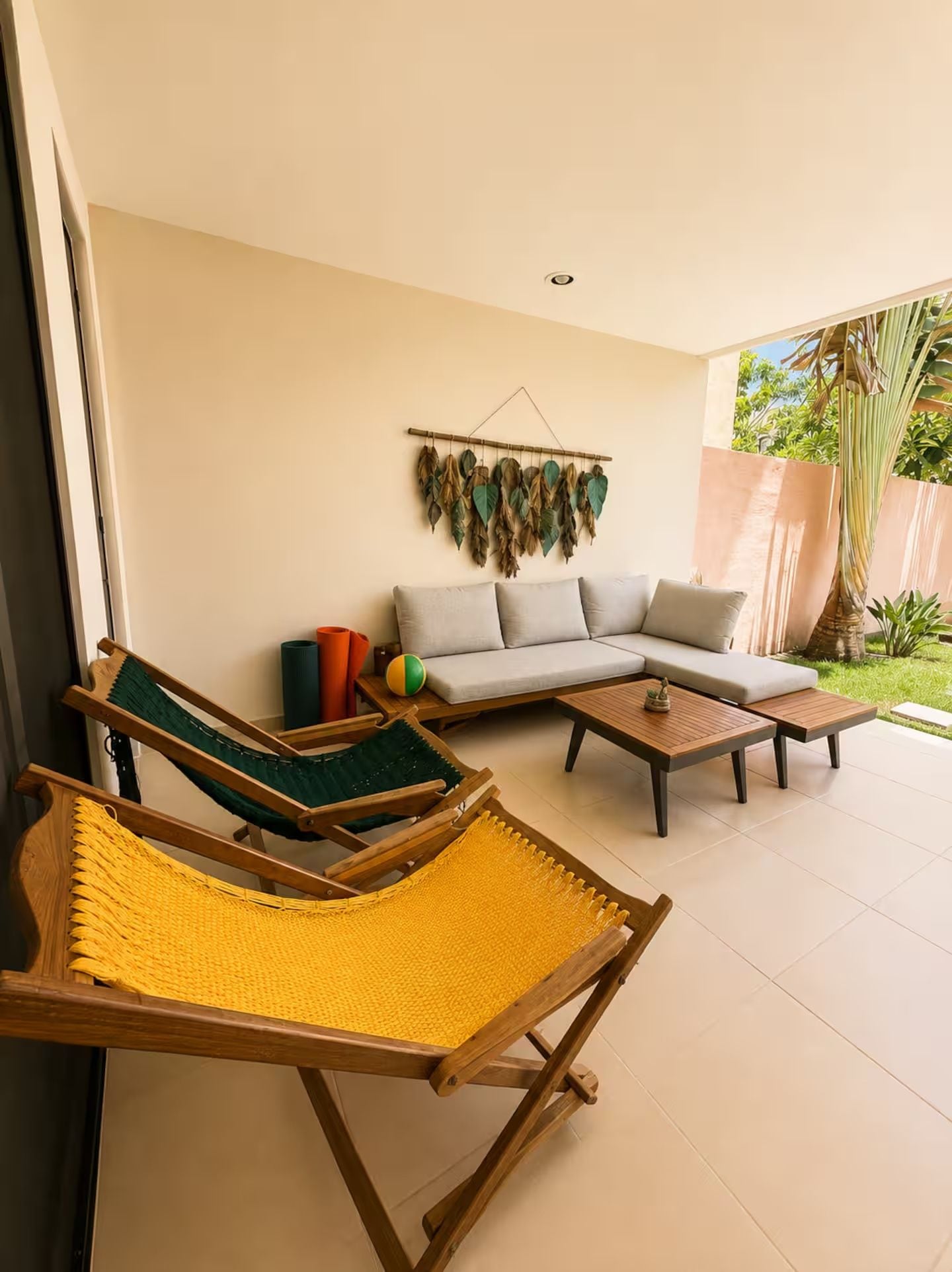 A modern living room with a sofa, two hammocks, a coffee table, and a wall-mounted plant display.